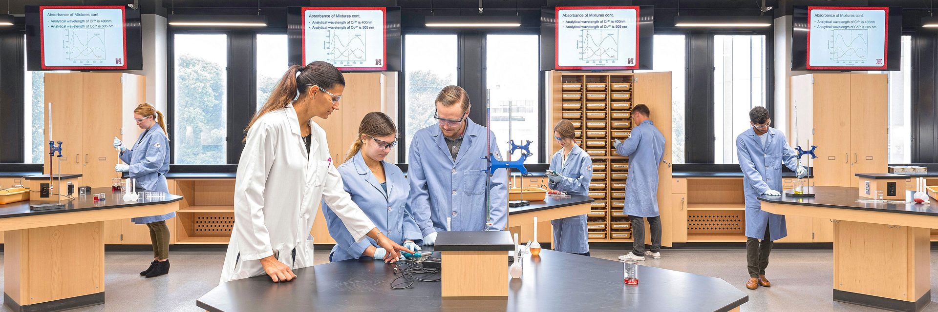 Chemistry professor demonstrating use of equipment to two students in a modern teaching laboratory
