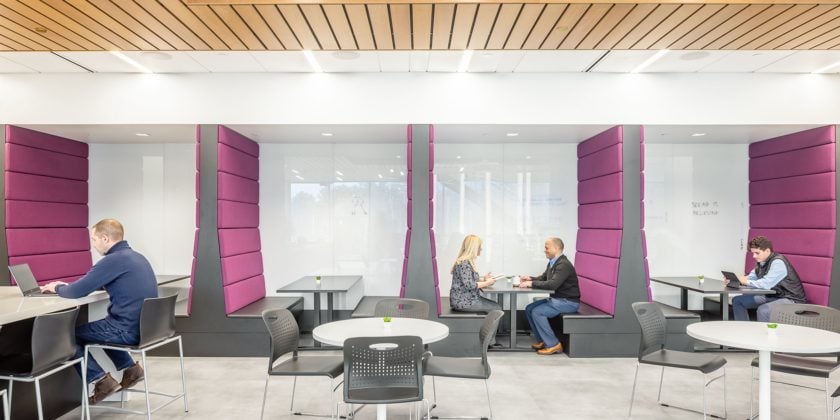 Collaboration booths in centralized cafe area showcase brand colors.